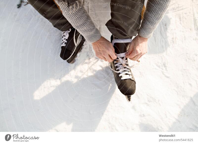 Mann zieht Schlittschuhe an Schlittschuhläufer Schlittschuhlaeufer anziehen anlegen Schlittschuhlaufen Eislaufen Wintersport Wintersportart Wintersportarten
