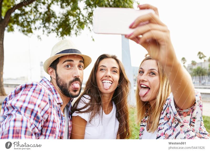 Drei Freunde machen ein Selfie und strecken ihre Zungen heraus Spaß Spass Späße spassig Spässe spaßig Handy Mobiltelefon Handies Handys Mobiltelefone Selfies