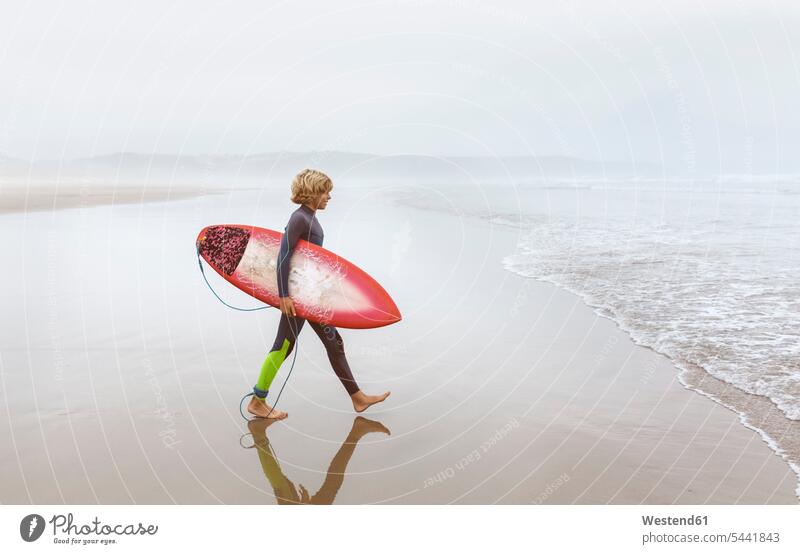 Spanien, Aviles, junger Surfer auf dem Weg zum Wasser Strand Beach Straende Strände Beaches Wellenreiter Surfbrett Surfbretter surfboard surfboards Teenager