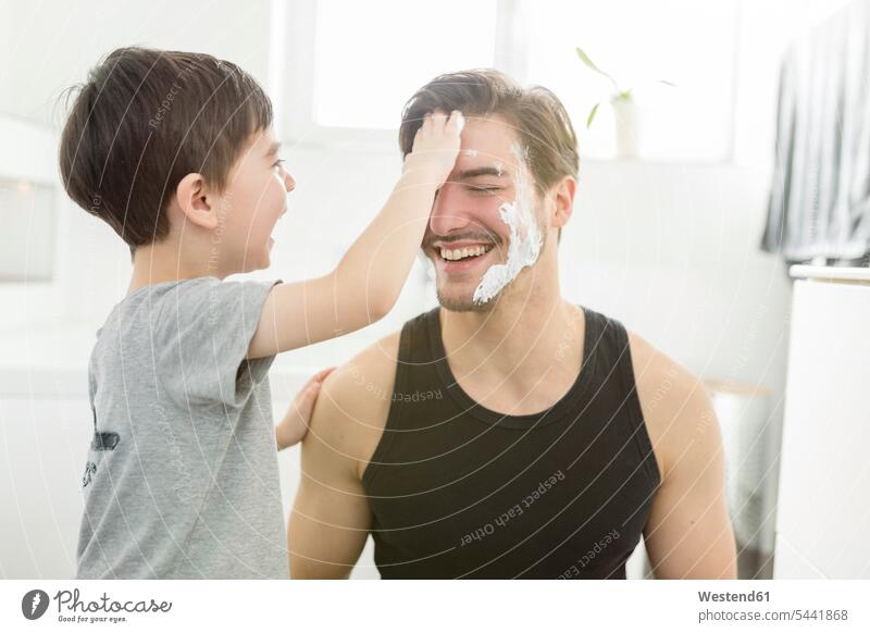 Verspielter Sohn trägt Rasierschaum auf das Gesicht des Vaters auf Söhne Papas Väter Vati Vatis Papis lachen anwenden auftragen Spaß Spass Späße spassig Spässe