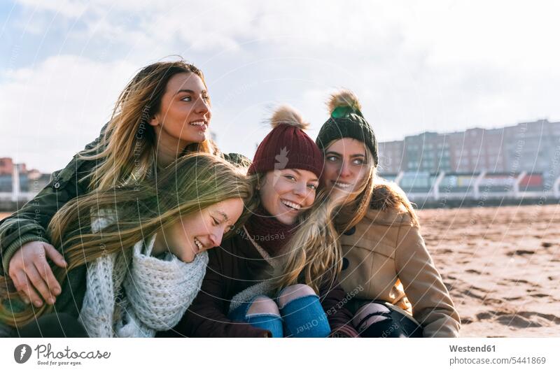 Vier glückliche Freunde verbringen gemeinsam Zeit am Strand Kameradschaft Freundin Beach Beaches Straende Strände Portraits Porträt Porträts Jahreszeiten