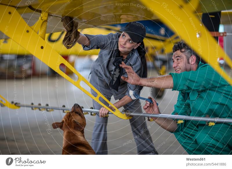 Mechaniker mit Hund im Hangar bei der Reparatur von Leichtflugzeugen Mechanikerin Mechanikerinnen Flugzeug Flieger Flugzeuge reparieren arbeiten Arbeit Monteur