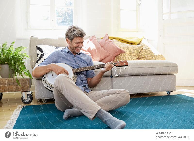 Mann sitzt auf dem Boden und spielt Banjo spielen Entspannung entspannt Entspannen relaxen entspannen Banjos Zuhause zu Hause daheim sitzen sitzend Böden Boeden