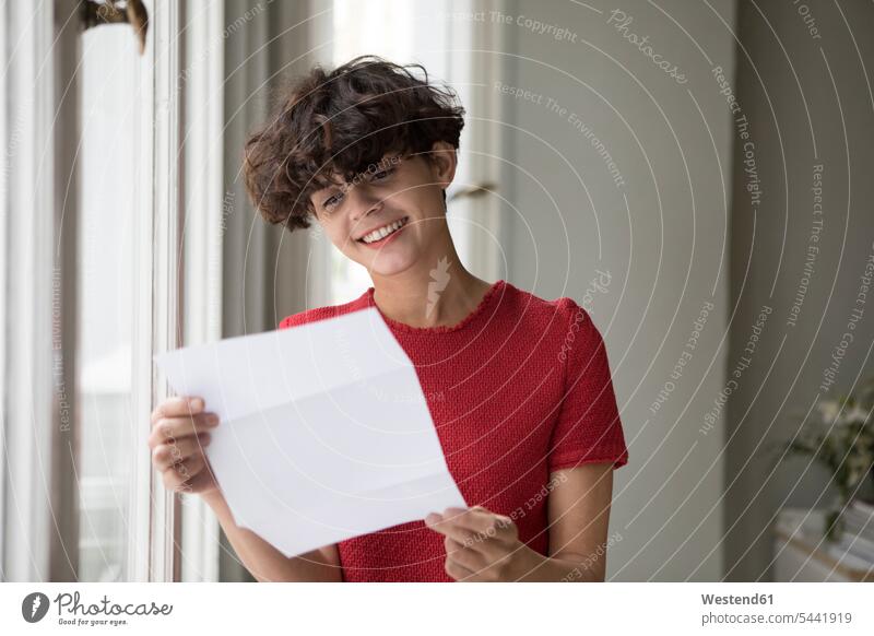 Porträt einer lächelnden jungen Frau beim Lesen eines Briefes weiblich Frauen lesen Lektüre Post Nachrichten Erwachsener erwachsen Mensch Menschen Leute People