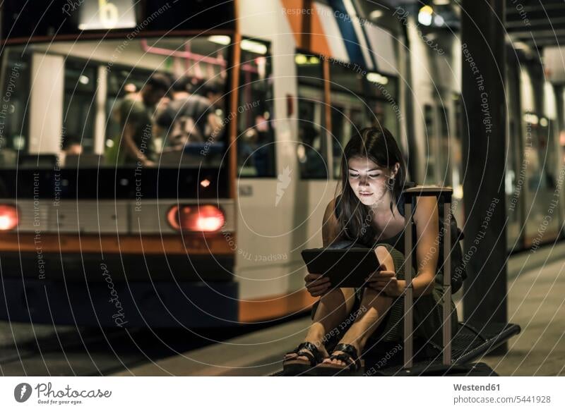 Porträt einer jungen Frau, die nachts an der Straßenbahnhaltestelle wartet und Tabletten benutzt Nacht weiblich Frauen Erwachsener erwachsen Mensch Menschen
