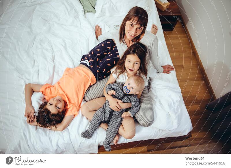 Glückliche Mutter mit ihren drei Kindern im Bett Familie Familien Portrait Porträts Portraits Mami Mutti Mütter Mama lächeln Betten Mensch Menschen Leute People