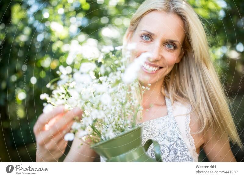 Lächelnde Frau hält Krug mit Blumen im Freien Blüte weiblich Frauen lächeln Pflanze Pflanzenwelt Flora Erwachsener erwachsen Mensch Menschen Leute People