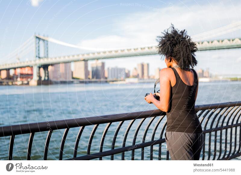 USA, New York City, Brooklyn, Frau am Wasser stehend steht weiblich Frauen Fluss Fluesse Fluß Flüsse Brücke Bruecken Brücken Erwachsener erwachsen Mensch