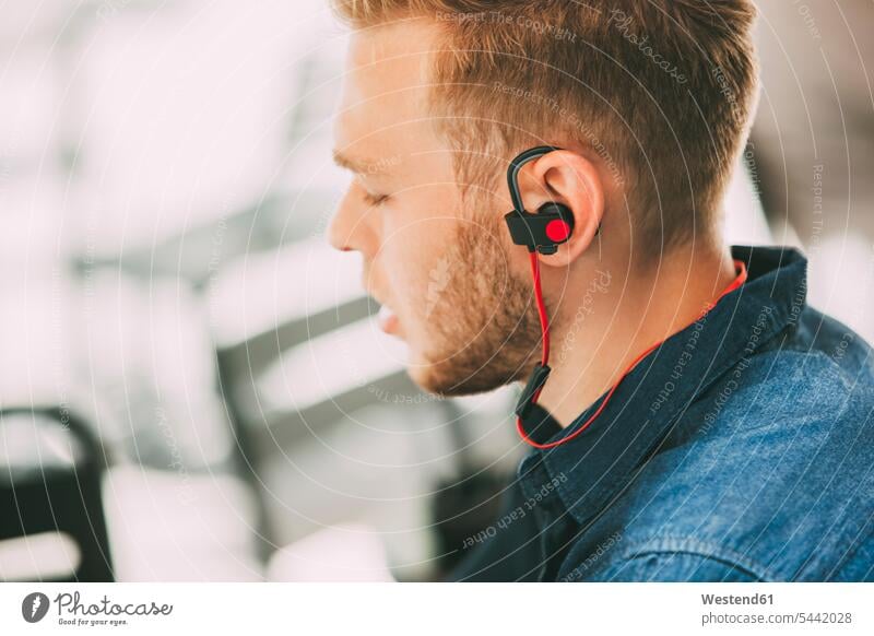 Junger Mann trägt Kopfhörer im Freien Kopfhoerer Ohrhörer Männer männlich In-Ear Erwachsener erwachsen Mensch Menschen Leute People Personen hören hoeren Musik