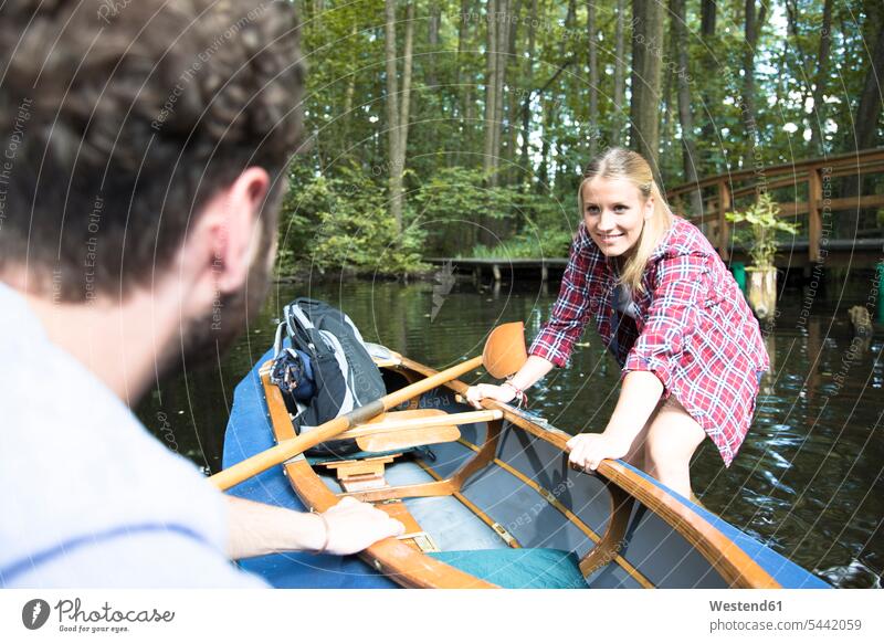 Glückliches junges Paar beim Einsteigen ins Kanu in einem Waldbach einsteigen Bach Bäche Baeche Pärchen Paare Partnerschaft glücklich glücklich sein