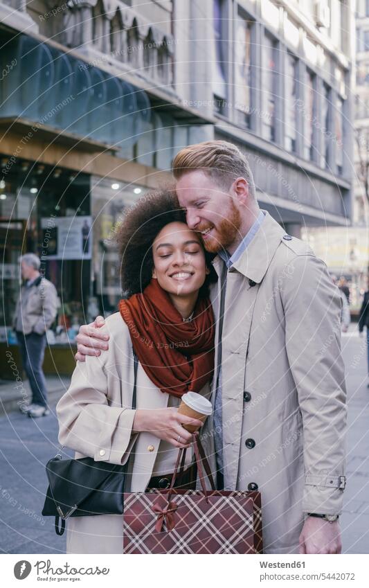 Glückliches Paar beim Einkaufen in der Stadt Pärchen Paare Partnerschaft lächeln Shopping einkaufen shoppen umarmen Umarmung Umarmungen Arm umlegen Mensch