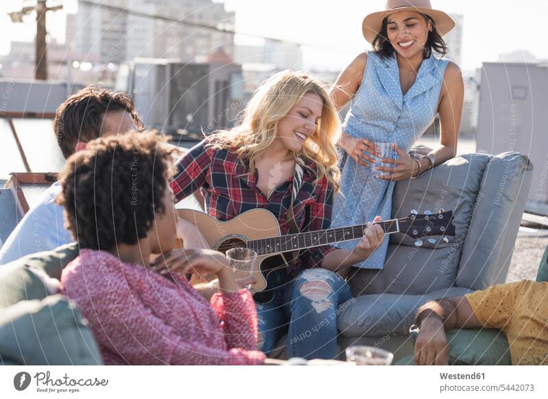 Freunde feiern eine Party auf dem Dach und spielen Gitarre Dachterrasse Dachterrassen lachen Parties Partys Gitarren positiv Emotion Gefühl Empfindung Emotionen