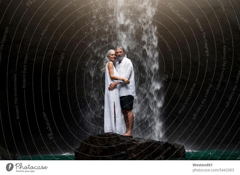 Zärtliches älteres Ehepaar steht vor einem tropischen Wasserfall Gemeinsam Zusammen Miteinander stehen stehend umarmen Umarmung Umarmungen Arm umlegen attraktiv