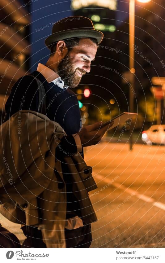 Stilvoller junger Mann mit Tablette auf nächtlicher Stadtstraße lächeln Tablet Computer Tablet-PC Tablet PC iPad Tablet-Computer Nacht nachts Männer männlich