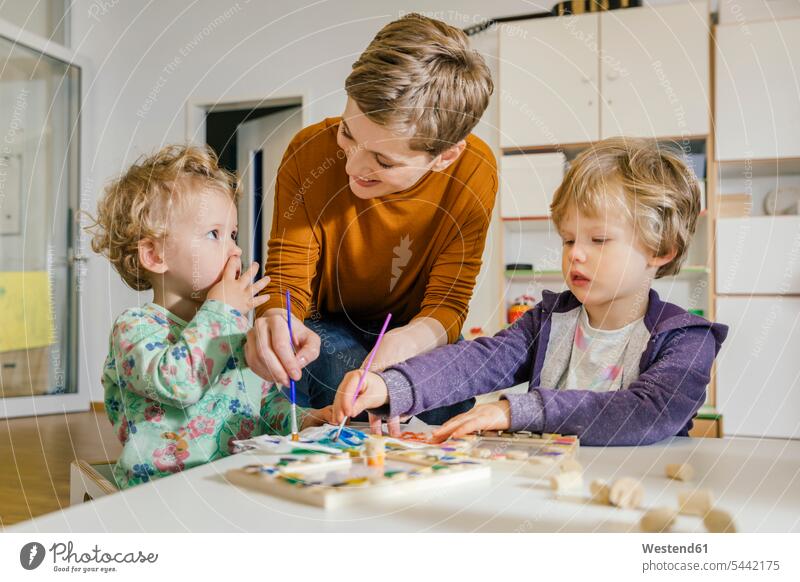 Vorschullehrerin malt mit zwei Kindern im Kindergarten Erzieherin Mensch Bildung Pädagogik Einsatz Innenaufnahme Deutschland Vorschule lächeln Freude Pinsel