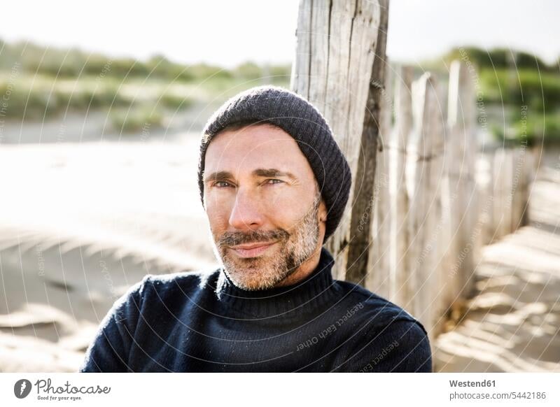 Porträt eines lächelnden Mannes am Zaun am Strand entspannt entspanntheit relaxt Beach Straende Strände Beaches Männer männlich Portrait Porträts Portraits