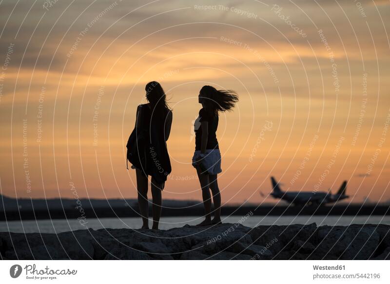 Indonesien, Bali, zwei Frauen beobachten den Sonnenuntergang über dem Ozean Sonnenuntergänge Freundinnen Meer Meere Küste Kueste Kuesten Küsten Stimmung