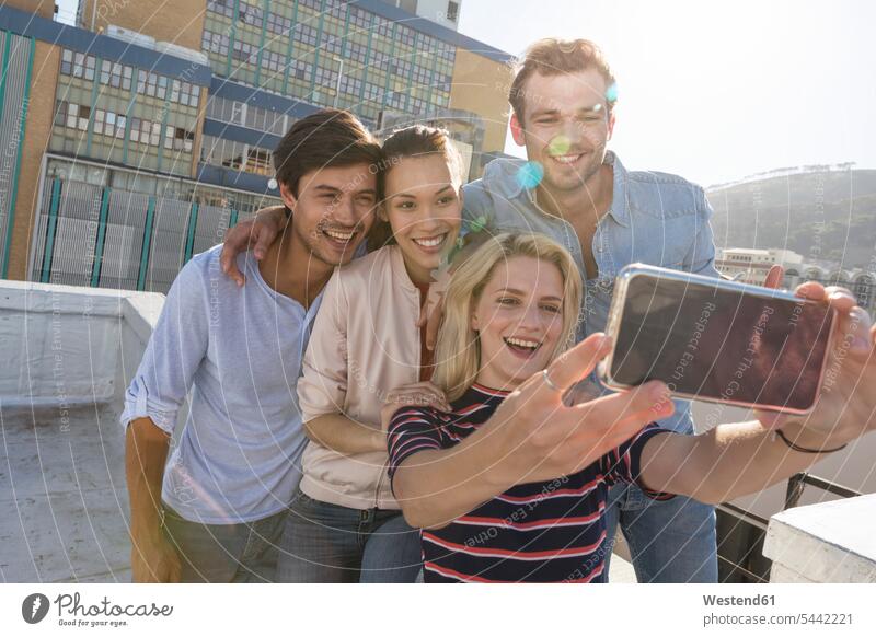Freunde machen Selfies auf einer Dachterrasse fotografieren lächeln Dachterrassen feiern Kamera Kameras Freundschaft Kameradschaft Fotoapparat Fotokamera