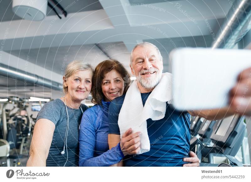 Gruppe von fitten Senioren im Fitnessstudio, die nach dem Training ein Selfie mit ihrem Smartphone machen alte ältere Handy Mobiltelefon Handies Handys
