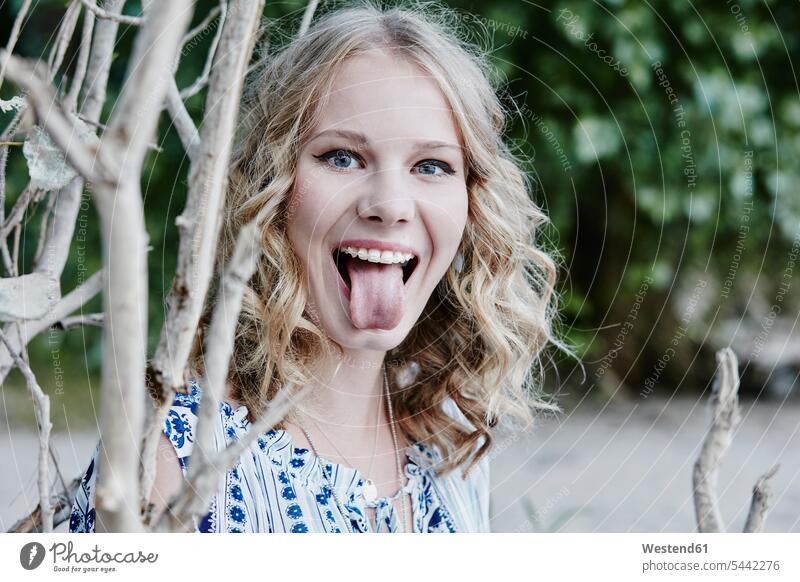 Porträt eines Teenagers mit herausgestreckter Zunge in der Natur frech Frechheit Teenagerin junges Mädchen Teenagerinnen weiblich junge Frau Portrait Porträts