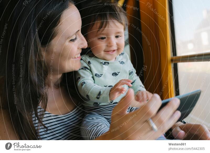 Glückliche Mutter und kleines Mädchen benutzen Smartphone während der Zugfahrt Handy Mobiltelefon Handies Handys Mobiltelefone reisen verreisen Baby Babies
