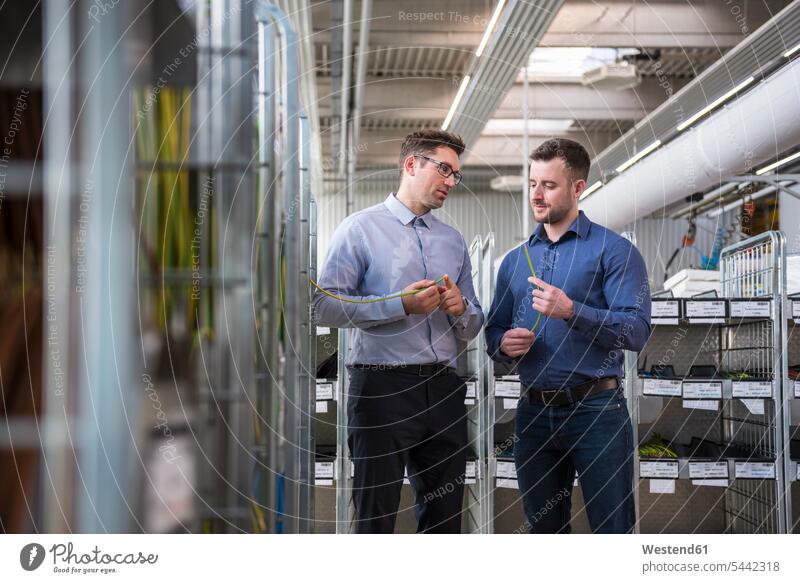 Zwei Männer in Fabrikhalle untersuchen Produkt arbeiten Arbeit Mann männlich Fabriken Kollegen Arbeitskollegen Erwachsener erwachsen Mensch Menschen Leute