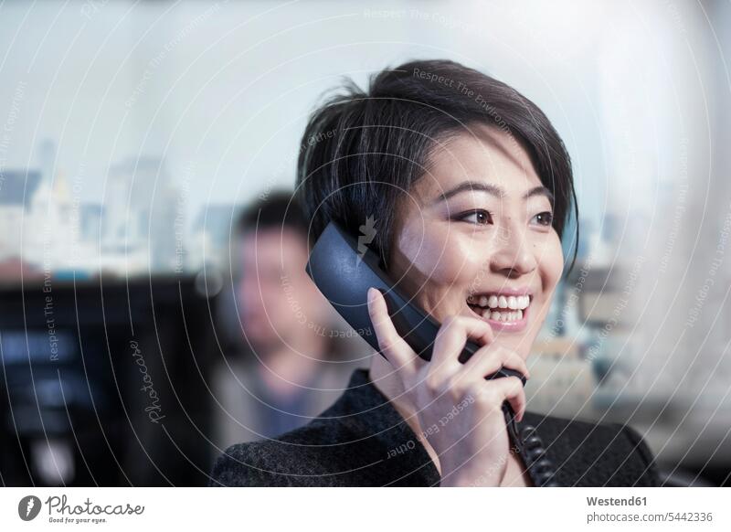 Lächelnde Frau im Büro telefoniert lächeln weiblich Frauen telefonieren anrufen Anruf telephonieren Geschäftsfrau Geschäftsfrauen Businesswomen Businessfrauen