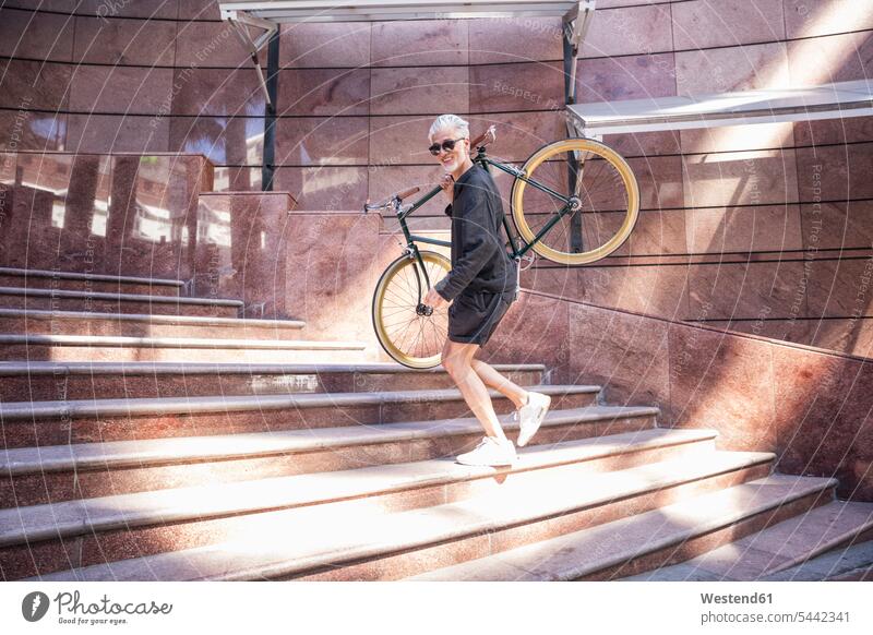 Erwachsener Mann trägt sein Fahrrad auf den Schultern Bikes Fahrräder Räder Rad Treppensteigen tragen transportieren radfahren fahrradfahren radeln Männer