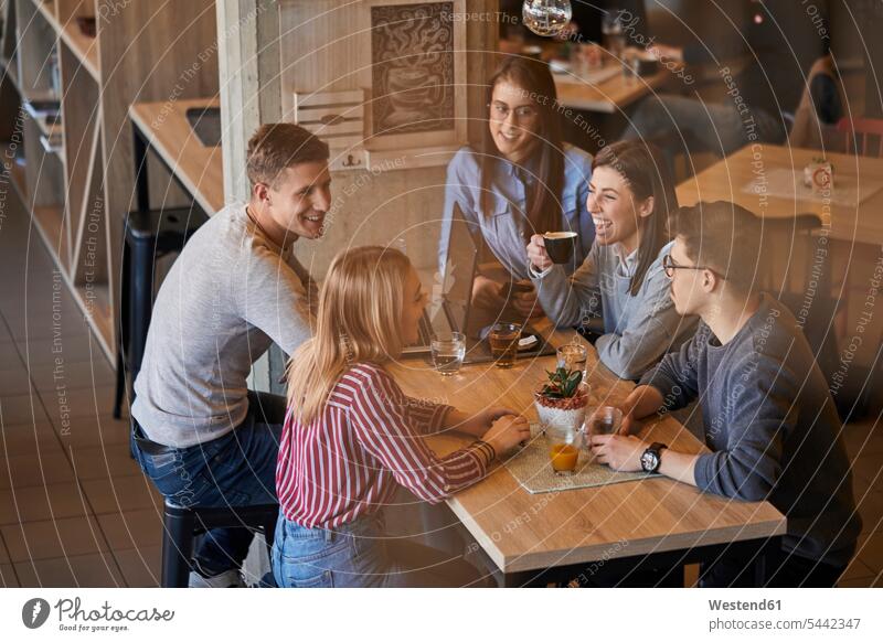 Gruppe glücklicher Freunde sitzt zusammen in einem Café mit Laptop und Getränken Cafe Kaffeehaus Bistro Cafes Cafés Kaffeehäuser Gemeinsam Zusammen Miteinander
