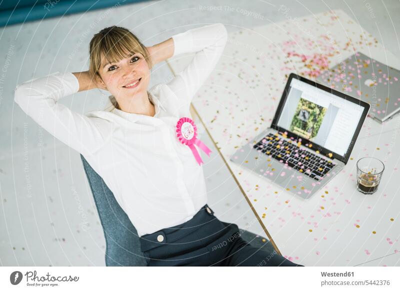 Porträt einer lächelnden Geschäftsfrau mit Laptop im Büro, die ihren Geburtstag feiert Office Büros Notebook Laptops Notebooks Geburtstagsfeiern Geburtstage