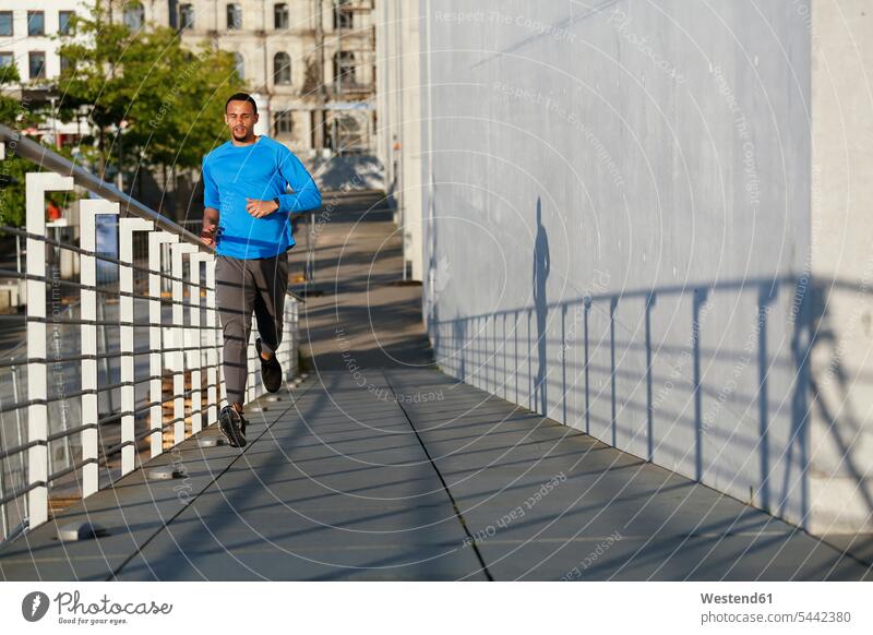 Junger Mann läuft auf einer Fußgängerbrücke in der Stadt Männer männlich Joggen Jogging trainieren laufen rennen Erwachsener erwachsen Mensch Menschen Leute