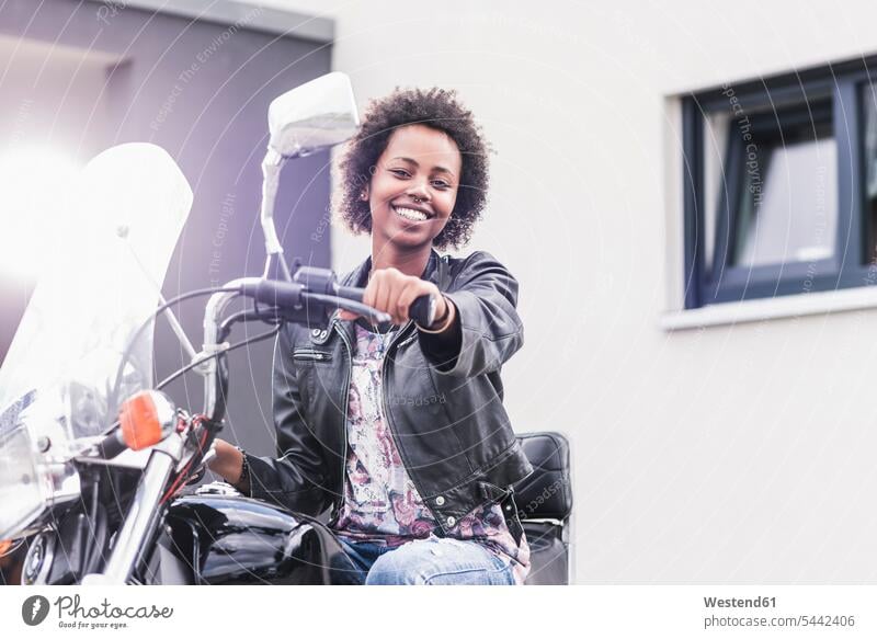 Porträt einer lächelnden jungen Frau mit ihrem Motorrad Motorräder weiblich Frauen Kraftfahrzeug Verkehrsmittel KFZ Erwachsener erwachsen Mensch Menschen Leute