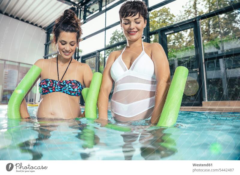 Zwei schwangere Frauen machen Wassergymnastik im Hallenbad Hallenbäder Hallenbaeder Schwangere Aqua Aerobic weiblich Schwimmbad Schwimmbaeder Schwimmbäder