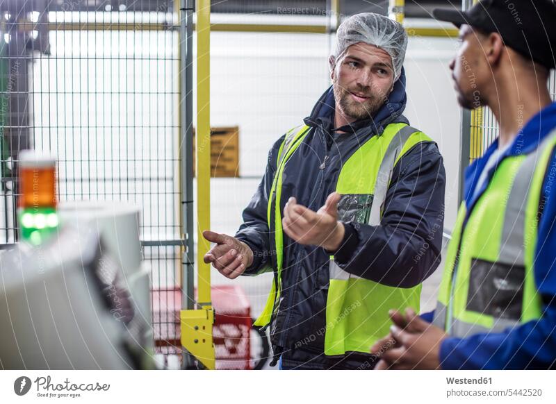 Zwei Arbeiter diskutieren in der Fabrik Mann Männer männlich sprechen reden arbeiten Kollegen Arbeitskollegen Fabrikgebäude Fabrikgebaeude Fabriken Erwachsener