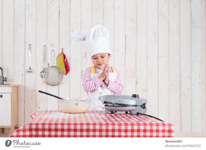 Kleines Mädchen, das Waffeln zubereitet und eine Kochmütze trägt backen Teig stehen stehend steht Küche weiblich Essen Food Food and Drink Lebensmittel