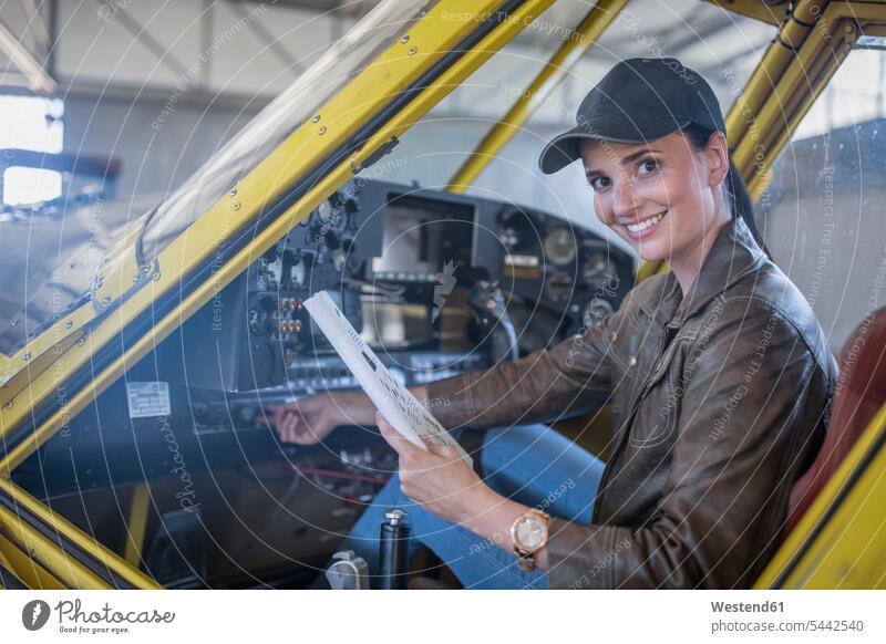 Weibliche Pilotin inspiziert Leichtflugzeug-Cockpit inspizieren prüfen überprüfen testen checken sitzen sitzend sitzt Pilotinnen Flugzeug Flieger Flugzeuge