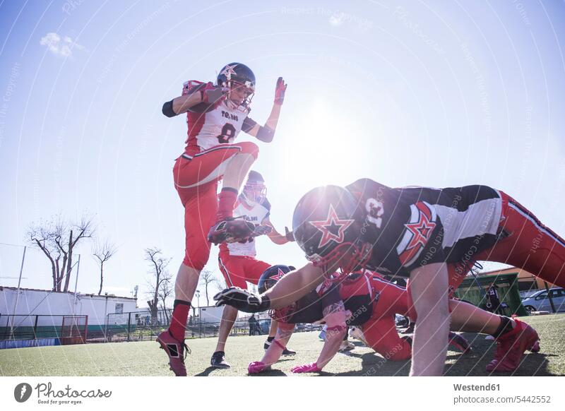American-Football-Spieler, der während eines Spiels mit dem Ball springt Helm Helme American Football Match springen hüpfen Sport Sprung Spruenge Sprünge