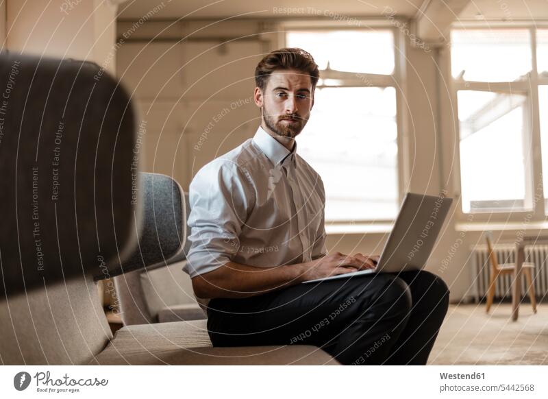 Porträt eines jungen Geschäftsmannes mit Laptop in einem Loft Notebook Laptops Notebooks Businessmann Businessmänner Geschäftsmänner Computer Rechner