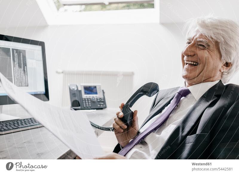 Lachender Senior-Geschäftsmann am Telefon in seinem Büro Telefonhörer Hörer Office Büros Businessmann Businessmänner Geschäftsmänner telefonieren Kommunikation