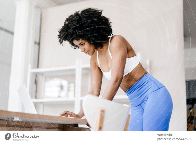 Fitte junge Frau mit Laptop zu Hause Online Training trainieren weiblich Frauen fit lernen arbeiten Arbeit Notebook Laptops Notebooks Internet Technologie