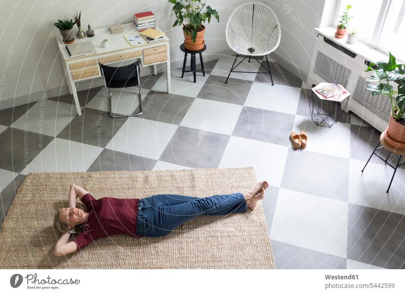 Entspannte reife Frau, die zu Hause auf dem Boden liegt weiblich Frauen Böden Boeden liegen liegend entspannt entspanntheit relaxt Erwachsener erwachsen Mensch