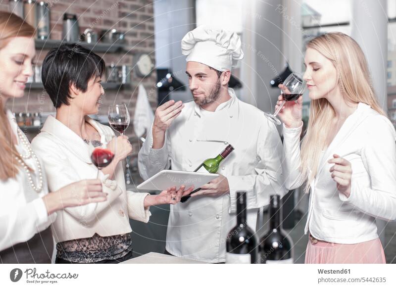 Koch mit drei Frauen, die in der Küche Rotwein probieren Rotweine Küchenchefs Köche Koeche Kuechenchef Kuechenchefs Kochkurs Wein Weine Alkohol
