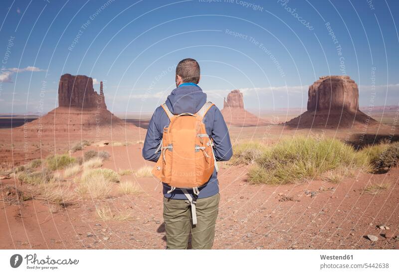USA, Utah, Rückenansicht eines Mannes mit Rucksack beim Blick auf das Monument Valley Männer männlich Tourist Touristen Erwachsener erwachsen Mensch Menschen