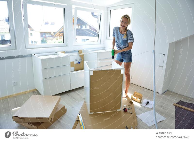 Frau, die zu Hause einen Schrank zusammenbaut aufbauen weiblich Frauen Heimwerken Do-it-Yourself DIY Erwachsener erwachsen Mensch Menschen Leute People Personen