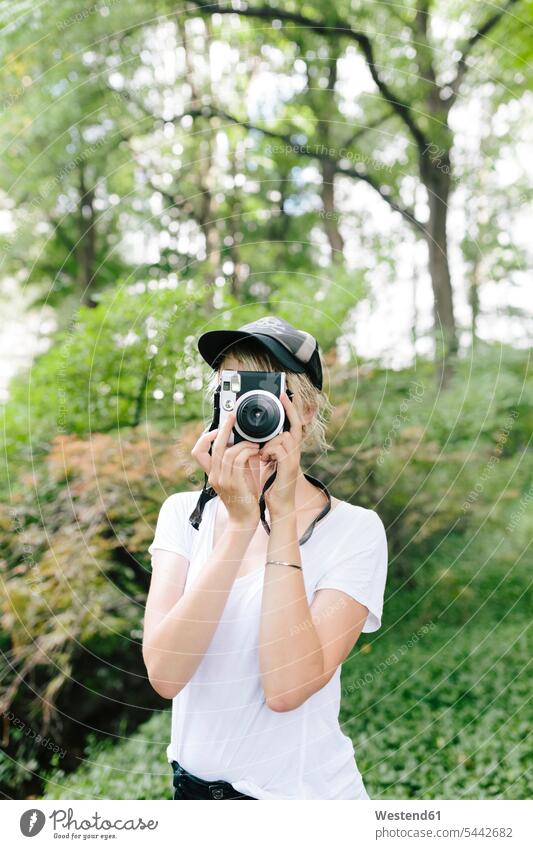 Junge Frau mit einer Oldtimer-Kamera beim Fotografieren im Park fotografieren Parkanlagen Parks Fotoapparat Fotokamera weiblich Frauen Erwachsener erwachsen