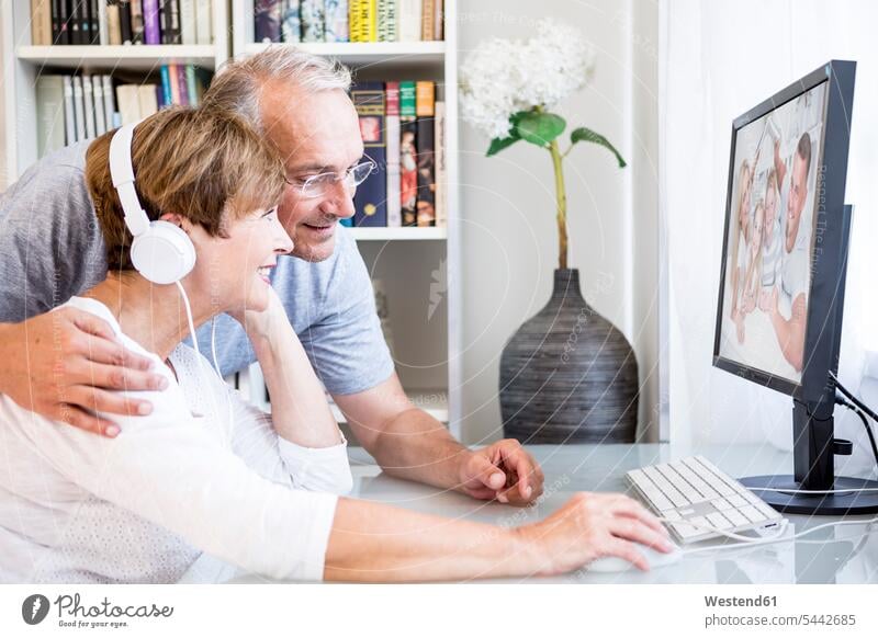 Älteres Ehepaar am Schreibtisch bei einer Videokonferenz mit ihrer Familie lächeln Paar Pärchen Paare Partnerschaft Mensch Menschen Leute People Personen modern