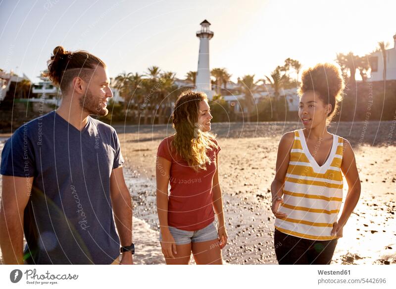 Spanien, Kanarische Inseln, Gran Canaria, drei Freunde beim Strandspaziergang in der Abenddämmerung Beach Straende Strände Beaches Freundschaft Kameradschaft