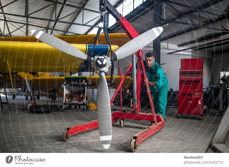 Mechaniker im Hangar, der den Propeller eines Leichtflugzeugs schiebt schieben anschieben Monteur Flugzeug Flieger Flugzeuge Reparatur arbeiten Arbeit