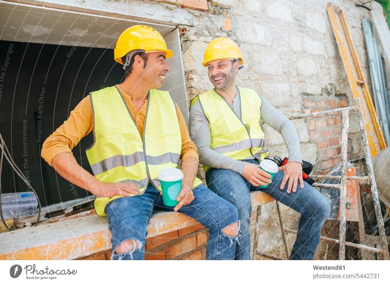 Bauarbeiter bei einer Kaffeepause auf der Baustelle Kollegen Arbeitskollegen lächeln Baustellen Pause sprechen reden Kommunikation Getränk Getraenk Getränke