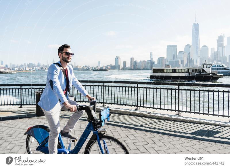 USA, Mann auf dem Fahrrad am Hafen von New Jersey mit Blick auf Manhattan Geschäftsmann Businessmann Businessmänner Geschäftsmänner New York New York State